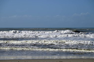 Tore del lago Puccini 'deki Akdeniz Sahili. Küçük güneşli sonbahar gökyüzü. Sudaki yansımalar.