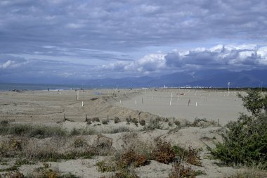 Tore del lago Puccini 'deki Akdeniz Sahili. Küçük güneşli sonbahar gökyüzü. Sudaki yansımalar.