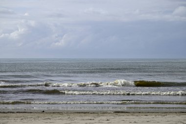 Tore del lago Puccini 'deki Akdeniz Sahili. Küçük güneşli sonbahar gökyüzü. Sudaki yansımalar.