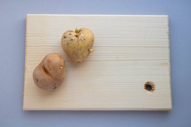 Masadaki tahta bir tahtanın üzerinde iki farklı kalp şeklinde patates var..