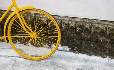 Sarı bir bisiklet tekerleği duvarın karşısında duruyor, klasik tarzda..