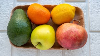 Beyaz tuğlalı arka planda çevre dostu ambalajda küçük bir meyve koleksiyonu..