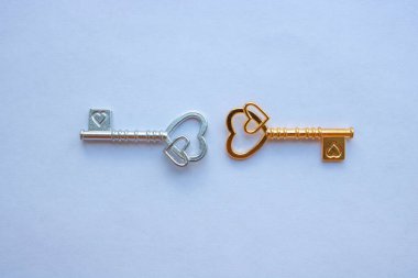 Altın ve gümüş anahtarlar, beyaz arka planda izole edilmiş kalpler..