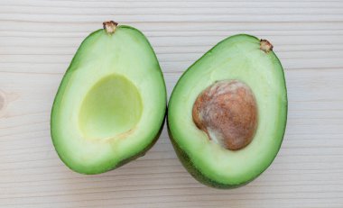 Olgun avokado dilimleri hafif bir kesim tahtasının üzerinde yatar..