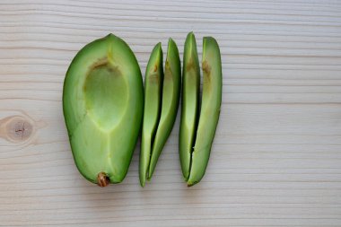 Olgun avokado dilimleri hafif bir kesim tahtasının üzerinde yatar..