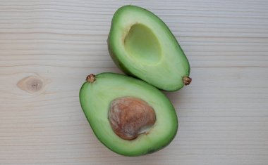 Olgun avokado dilimleri hafif bir kesim tahtasının üzerinde yatar..