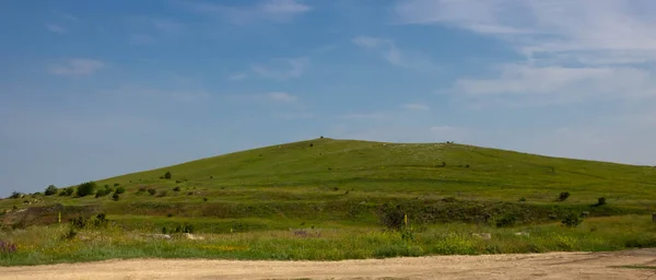 Een Groene Heuvel Een Zandweg Achtergrond Van Een Blauwe Lucht — Stockfoto