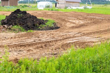 Siyah bir Chernozem yığını ve inşaat halindeki bir yol..
