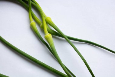 Sarımsaklı yeşil oklar beyaz arka planda yatıyor..