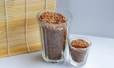 Keten tohumlu cam bir cam beyaz arka planda duruyor..