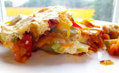 Beyaz tabakta çeşitli taze sebzelerden yapılmış sağlıklı renkli bir sebze lazanyası..