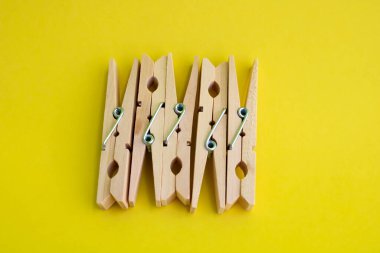 Sarı arka planda giysileri kurutmak için tahta mandallar..