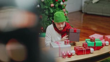 Çekici Asyalı erkekler oturma odasındaki hediye kutusunu işaretleyerek Noel ağacını evde kutluyor. Noel kutlaması kavramı.