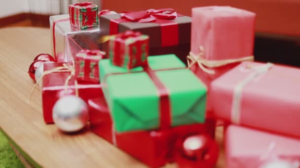 テーブルの上にクリスマスギフトボックスを閉じ 装飾品クリスマスは自宅のリビングルームで新年を祝います クリスマスお祝いのコンセプト — ストック動画