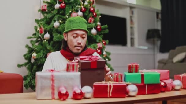 令人惊讶的是 亚洲男人在客厅里打开礼品盒 圣诞树在家里庆祝新年 圣诞庆祝概念 — 图库视频影像