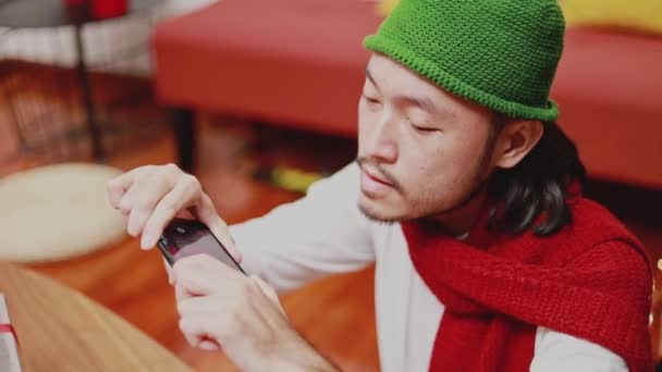 スマートフォンで写真を撮るアジアの男性を閉じますクリスマスツリーを飾る自宅のリビングルームで新年を祝います クリスマスお祝いのコンセプト — ストック動画