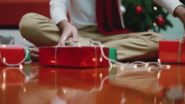 Fiatal Ázsiai Férfi Ajándékdobozt Készít Otthon Nappaliban Karácsonyfát Tart Háttérben — Stock videók