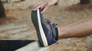 Atletik adam parkta egzersiz yapmadan önce bacak esneme hareketleri yapıyor..