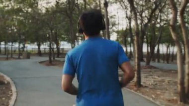 İzleme çekimi: Parkta koşarken kulaklık takan Asyalı sporcular müzik dinliyorlar. Sağlıklı yaşam tarzı kavramı.