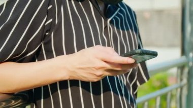Akıllı telefon kullanan bir genci kapatırken, çitin kenarında durup arkadaşlarına mesaj atıyor..