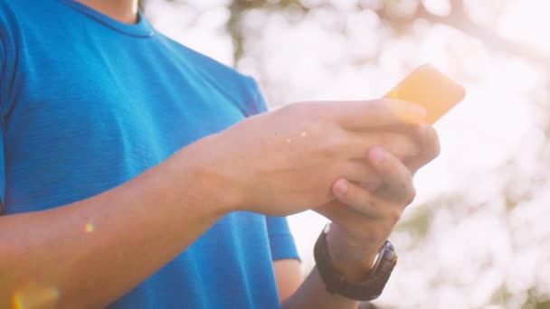 ランニング後は公園内のフェンスに立ちながら スマホでSnsをチェックし スマホで友達にメッセージを送る姿を間近で見ることができる — ストック動画