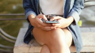 Yaz tatilinde Bangkok Tayland 'da nehir kenarında otururken akıllı telefon cihazları kullanan Asyalı kadının sosyal medyayı paylaşması.