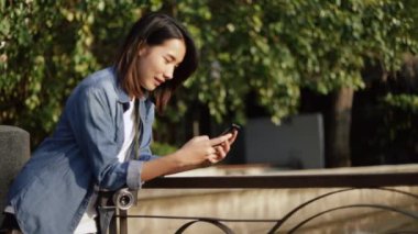 Güzel gün batımında Tayland 'da Chao Phraya nehrinin yanında durup arkadaşlarıyla akıllı telefon konuşarak gülümseyen Asyalı kadın. Tek başına yaz tatili tatili tatili..