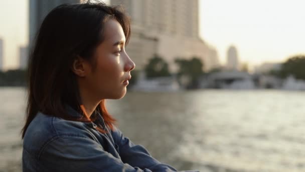 在美丽的落日下 站在泰国潮府河畔的年轻亚洲女子感到悲伤 — 图库视频影像