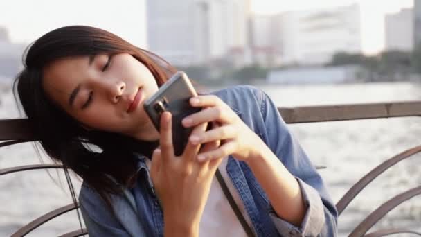 Happy Asian Female Using Smartphone Chatting Her Friends While Sitting — Stock Video