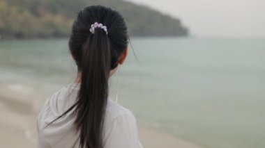 Spor kıyafetleri giymiş ve okyanus manzarasına bakarak müzik dinleyen mutlu güzel bir atlet kadın. çalışma sağlık yaşam tarzı konsepti.