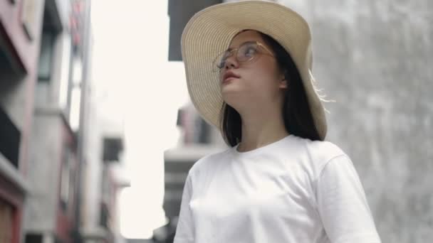 迷人的肖像画 年轻的亚洲女人 头戴穆斯林帽 戴着眼镜 环顾四周 环顾四周 旅行探索一个概念 暑假时间 — 图库视频影像
