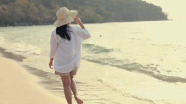 Güzel Asyalı kadın gün batımında sahilde yürüyor. Mutlu yaz tatilleri..