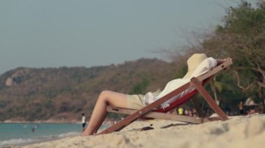 Sahildeki iskemlede yatan Asyalı kadın. Yaz tatilinde sahilde uyumak..