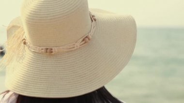 Asyalı kadın sahilde dururken denize bakıyor. Mutlu yaz tatili, güzel gün batımı..