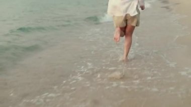 Sahilde koşan Asyalı gezgin, okyanusta güzel günbatımında eğleniyor. Yaşam tarzı seyahat tatil yaz tatili konsepti.