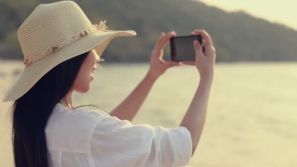 Прекрасна Азіатка Тримає Смартфон Робить Фото Пляжі Прекрасним Заходом Сонця — стокове відео