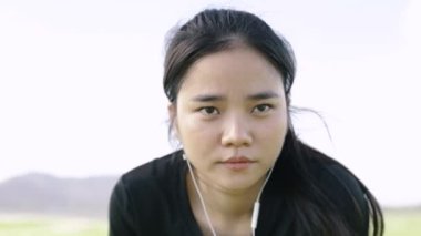 Yakın plan Asyalı atlet kadın sporcu kardiyo egzersizinden sonra yoruldu. Fitness ve sağlıklı bir yaşam tarzı. Kulaklık takan ve müzik dinleyen bir kız..