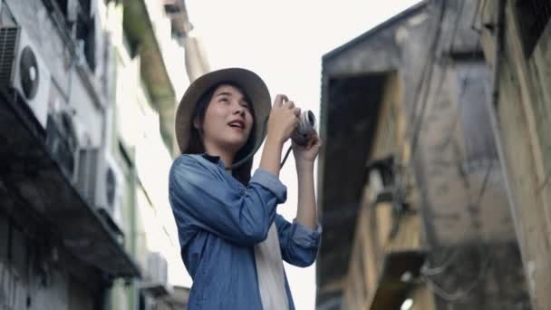 在泰国曼谷的一条小街上 一位戴着复古礼帽的亚洲女性游客用摄像相机拍照 她很开心 享受暑假旅行的乐趣 个人旅行概念 — 图库视频影像