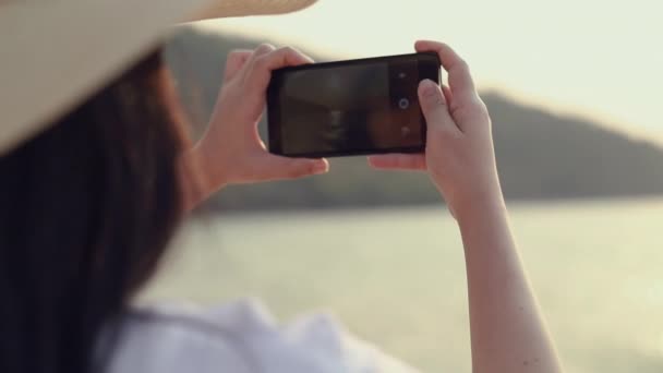 幸せなアジアの10代の女性は ビーチの美しい夕日に写真を撮るスマートフォンを保持 ライフスタイル旅行休暇夏のコンセプト — ストック動画