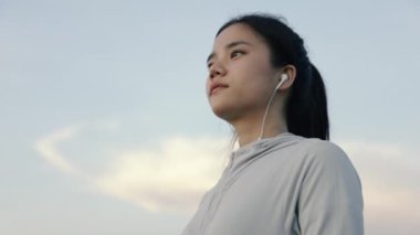 Portre güzel atletik Asyalı bayan koşucu gün batımı spor salonunda ve sağlıklı yaşam tarzı konseptinde koştuktan sonra dinleniyor..