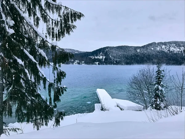 Frozen mountainous White Lake in winter in cloudy weather. Snow-covered wooden pier. Winter mountain landscape. British Columbia, Canada