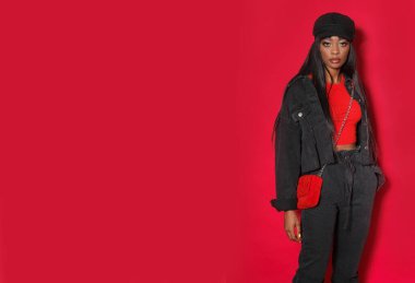 Profesyonel model kırmızı arka planda stüdyoda poz veriyor..