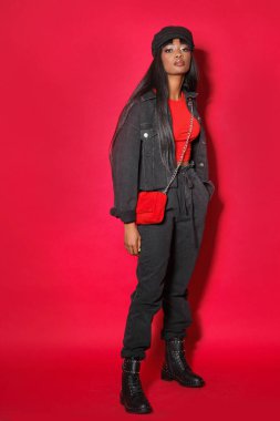 Profesyonel model kırmızı arka planda stüdyoda poz veriyor..