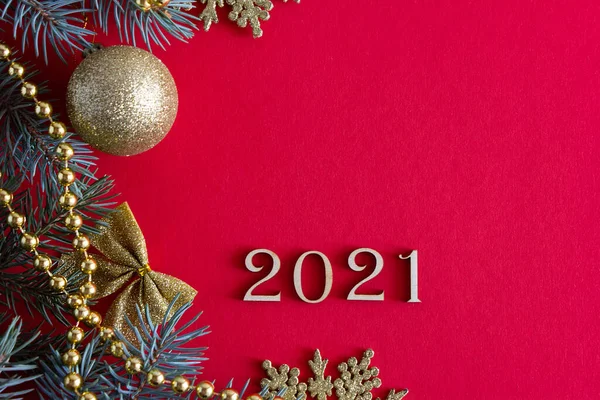 Napis z drewnianymi numerami 2021 na czerwonym tle Bożego Narodzenia z gałązkami jodły i zabawkami noworocznymi — Zdjęcie stockowe