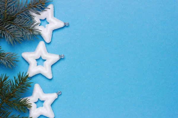 Beyaz yıldızlı Noel arkaplanı mavi arka planda ladin dalları, narin noel kartı