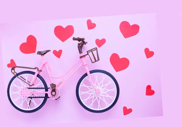 Rode harten en roze plastic fiets op een roze pastelachtergrond. het idee van liefde. Minimaal liefdesconcept — Stockfoto