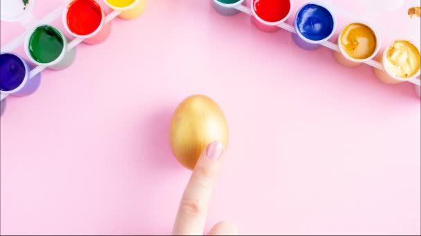 De hand van de meisjes verandert paaseieren in gekleurde eieren met haar vinger, creatieve kleuren van de eieren met verf en hand, stop beweging animatie — Stockvideo