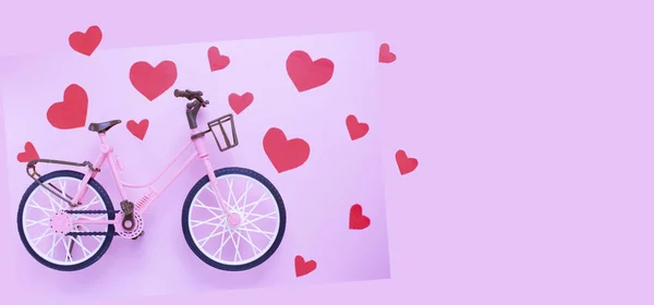 Red hearts and pink plastic bike on a pink pastel background. the idea of love. Love minimal concept. banner