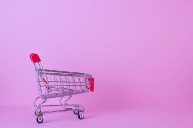 Pembe arka plandaki alışveriş arabasının fotokopi alanı ile yakın plan görüntüsü.