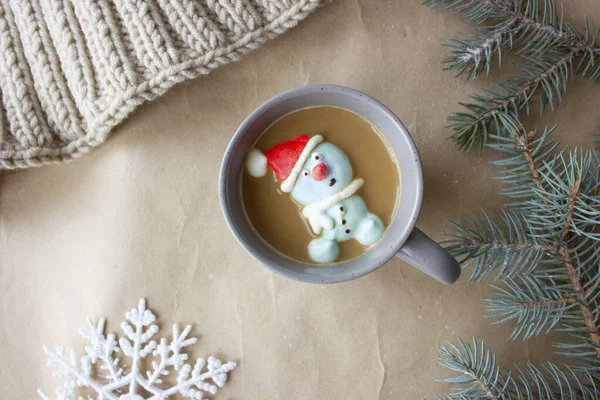 Composition de la nouvelle année, une tasse grise avec des guimauves de café sous la forme d'un bonhomme de neige dans un chapeau rouge. — Photo